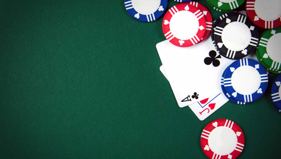 Aerial view of an ace and jack card next to some poker chips.