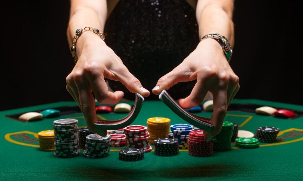 Hands holding playing cards over a green poker table.