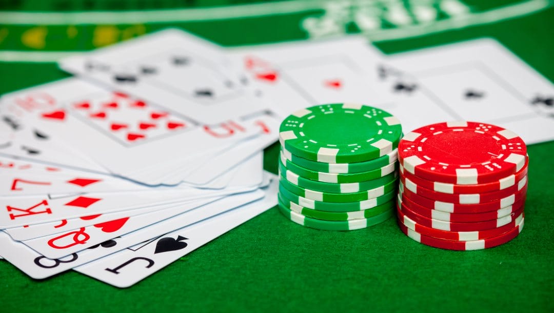 Playing cards and casino chips on a green felt table.