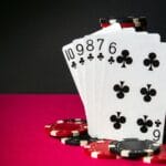 Playing cards featuring a straight flush surrounded by casino chips on a red poker table.