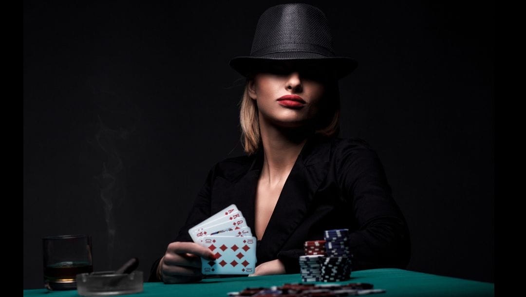 A mysterious woman wearing a hat that shades her eyes playing poker at a casino table.