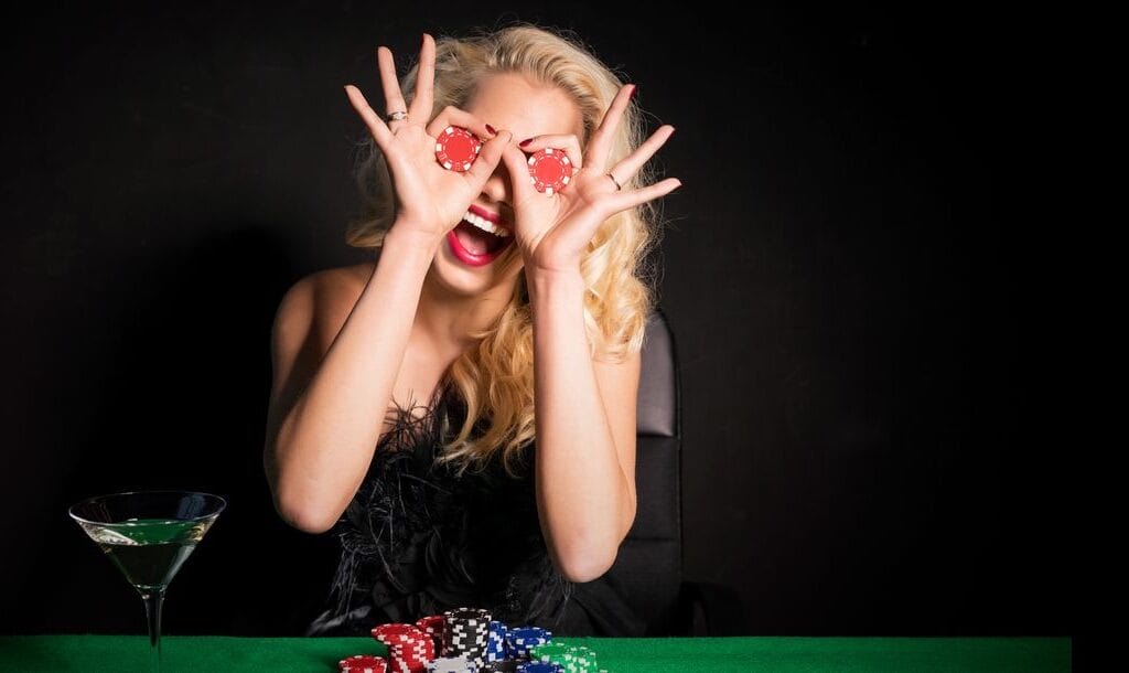 A woman holding poker chips to her eyes in a playful way.