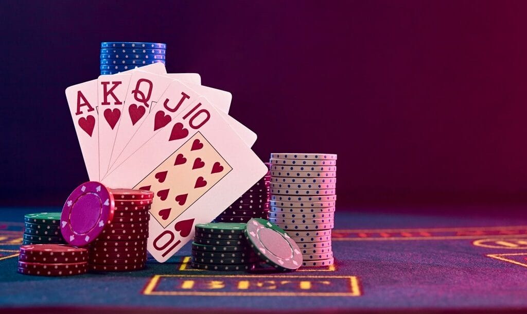 A royal flush propped up by casino chips on a casino game table.