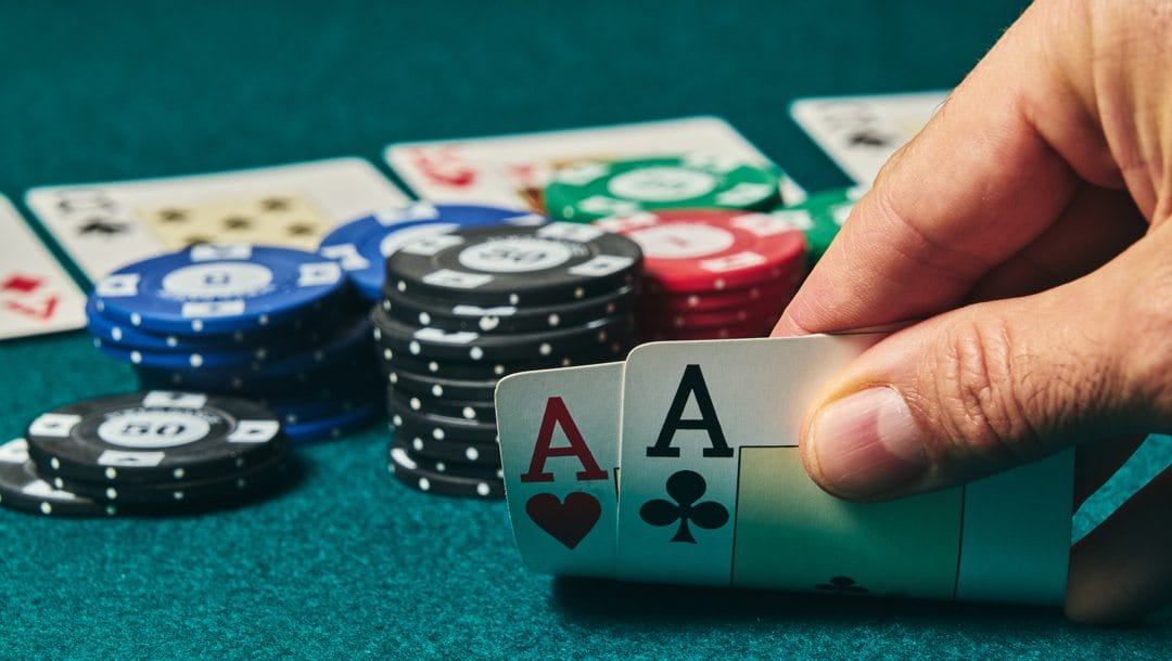 A poker player checks their hole cards and sees two aces.