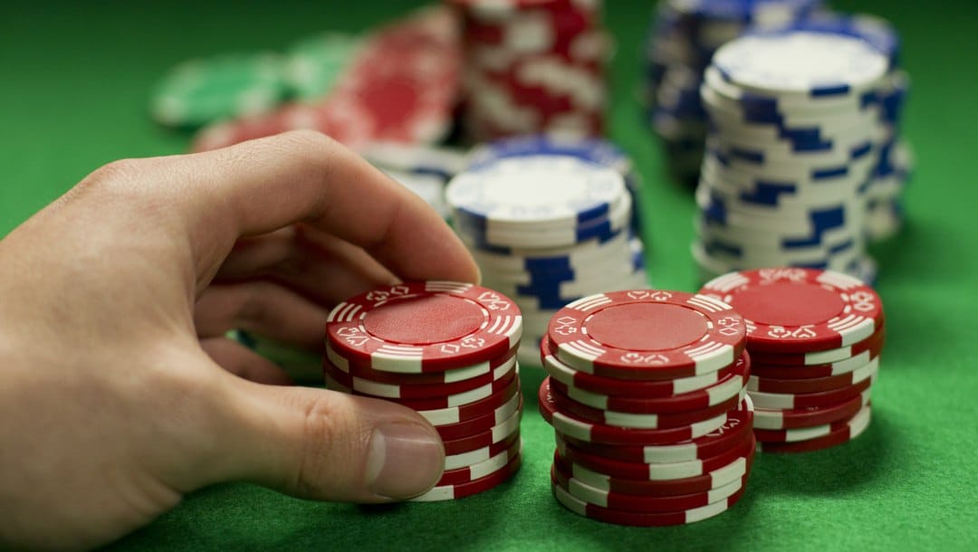 A gambler holding a stack of chips and deciding whether or not to bet.