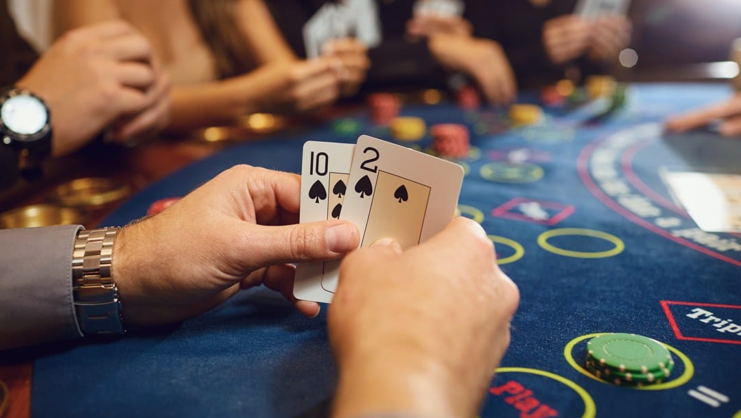 A close-up of a poker player holding a 2 and 10 of spades.