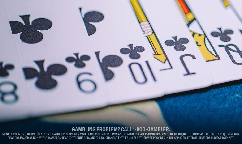 A close-up of playing cards—eight, nine, ten, jack, and queen of clubs—spread out on a table.