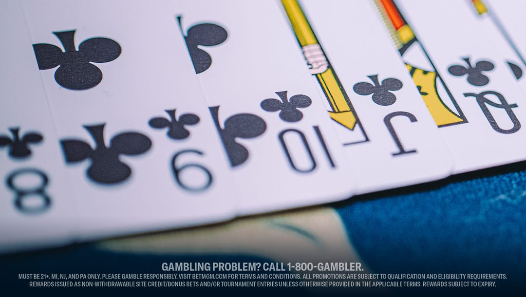 A close-up of playing cards—eight, nine, ten, jack, and queen of clubs—spread out on a table.