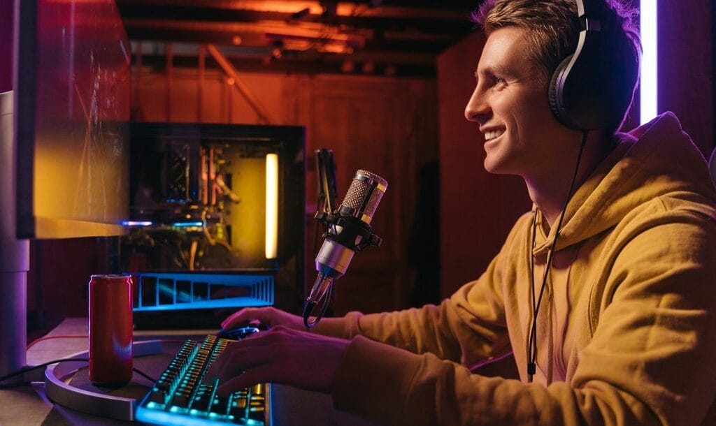 A young adult wearing headphones live-streams on a computer.