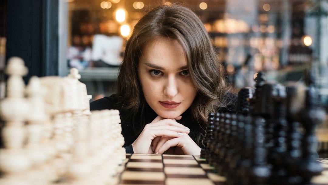 A woman focussing intensely on a chess board.