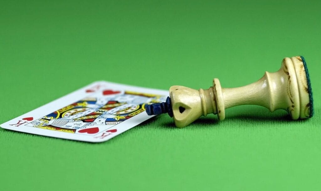 A playing card and chess piece on a green felt table.