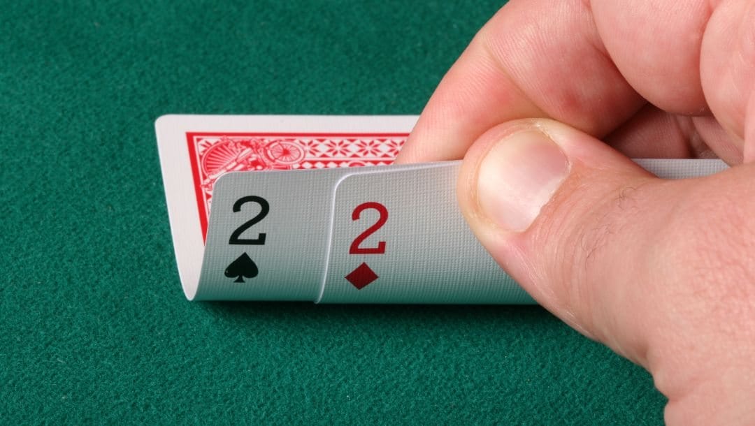 Player checks is hole cards of a pocket pair of twos on a poker table