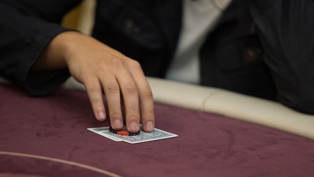 Man picking up his starting hand of two cards