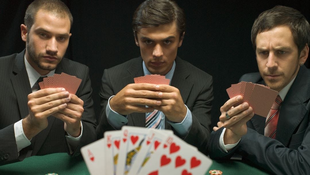 Men playing poker, with three of them staring back at the player who holds a royal flush