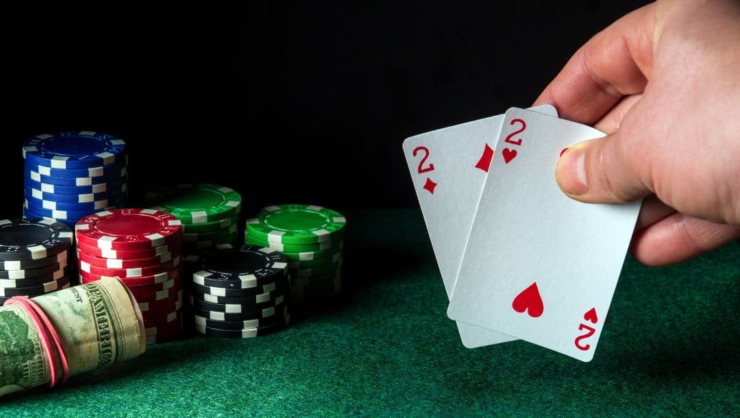 Man holding a pair of two’s with poker chips and money on the table