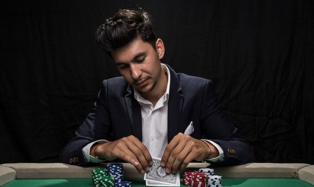 A professional poker player looking at his cards with stacks of chips surrounding them.