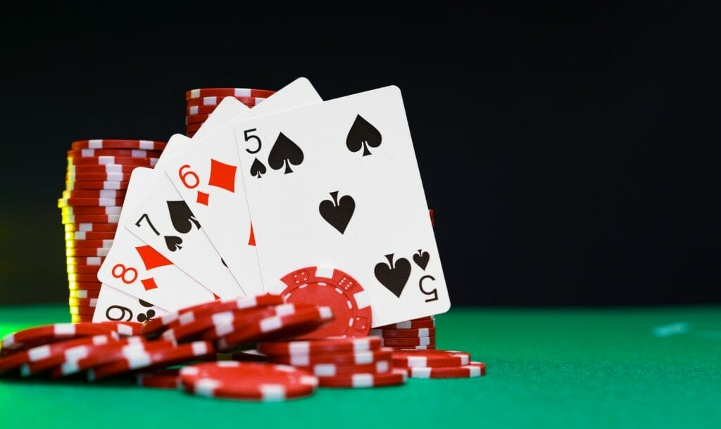 Playing cards and red casino chips on a green felt table.