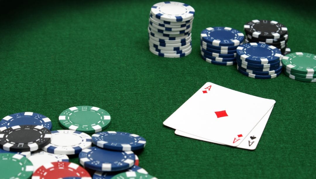 Ace playing cards and poker chips on a green felt table.
