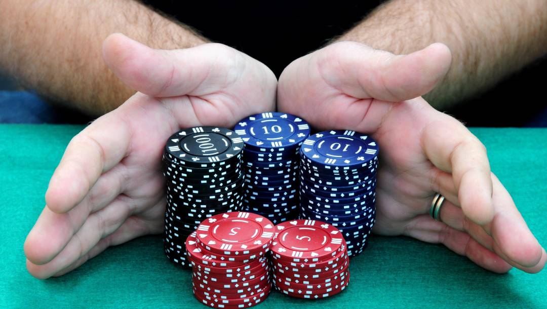 Two hands pushing five stacks of chips into the pot.