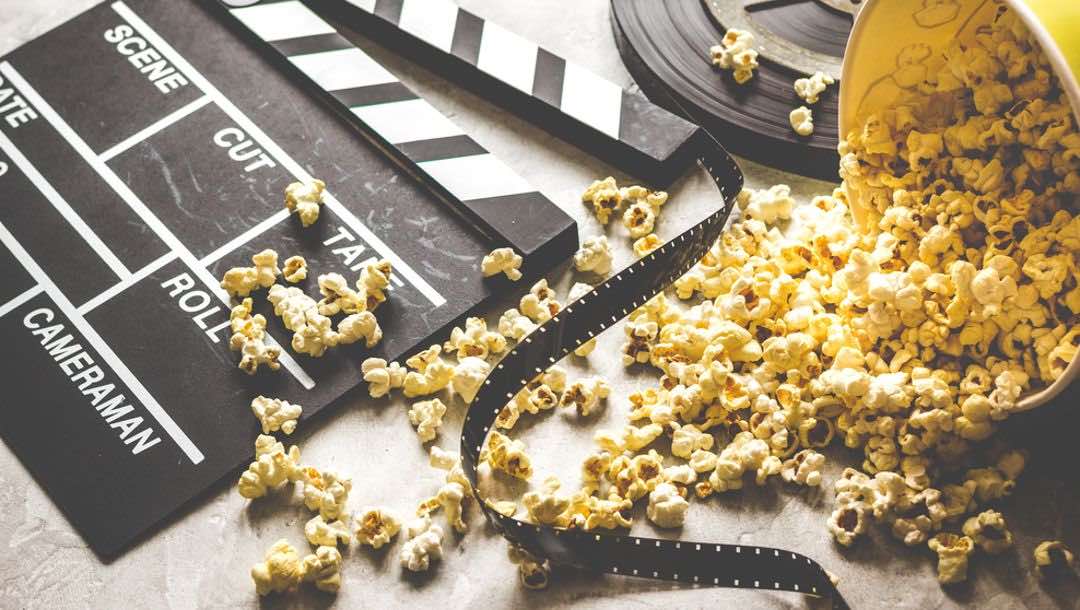 A big tub of popcorn and a film clapper board.