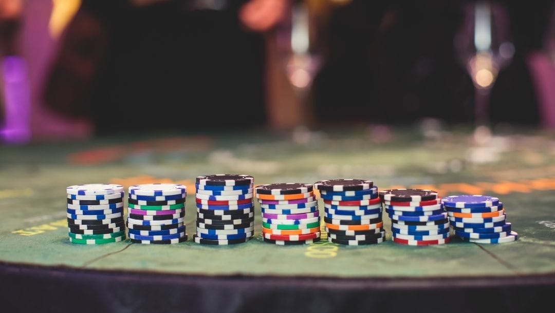 Multi-colored poker chips stacked next to each other on a green felt poker table in a casino