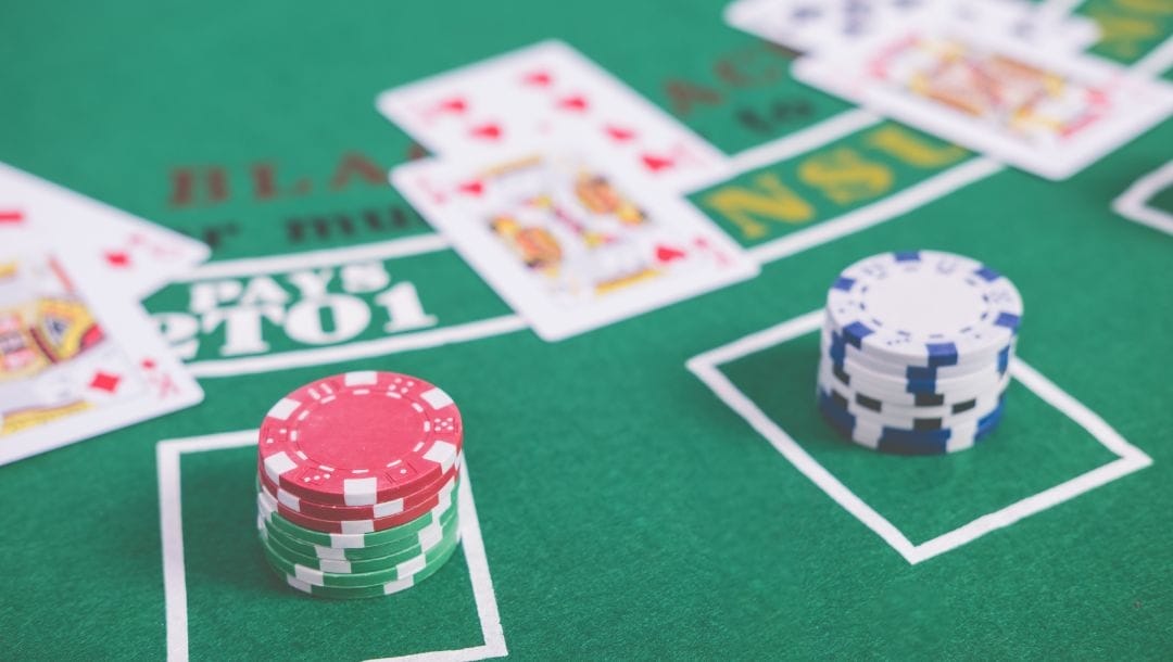 Poker chips and playing cards on a green felt blackjack poker table
