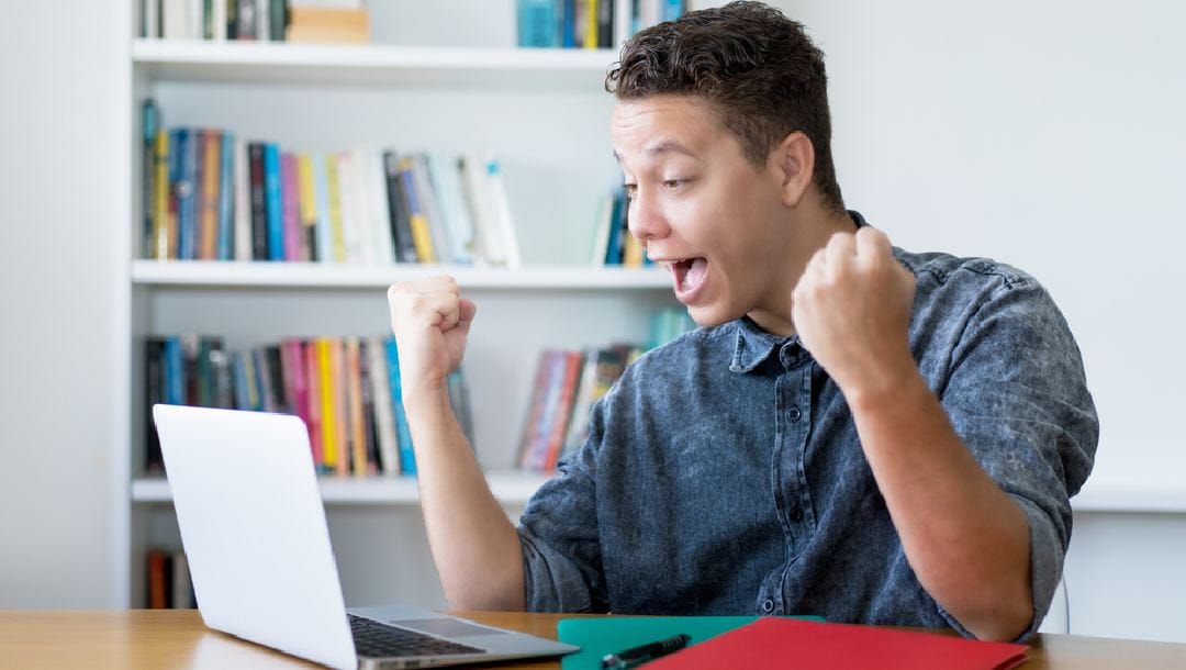A man celebrates winning a game on his laptop