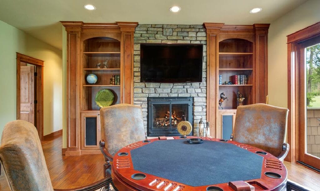 A round card games table in a front room with a TV and fireplace