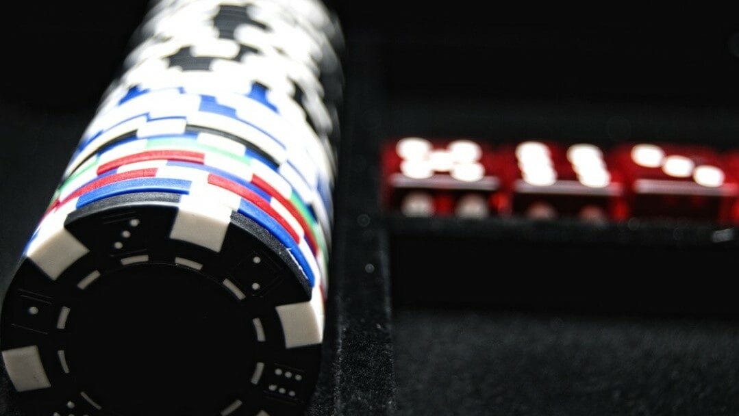 A line of poker chips next to three dice.