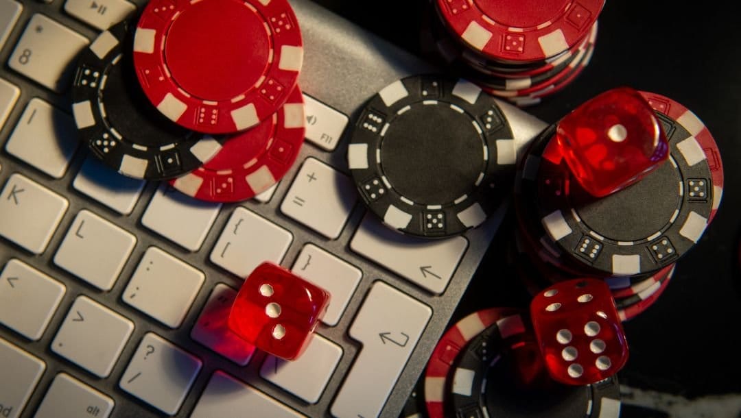 red and black poker chips and six-sided red dice on a computer keyboard