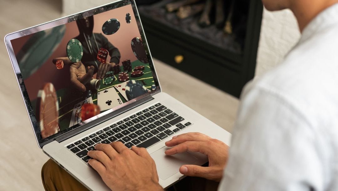 a person sitting down with a laptop resting on their lap that displays an online poker concept