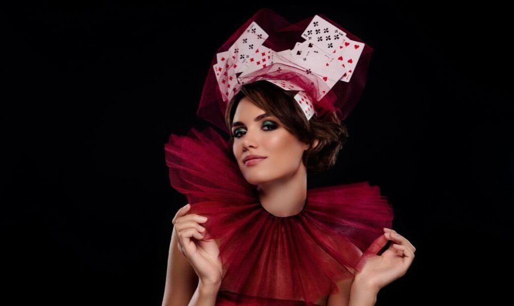 a woman dressed up in maroon tulle fabric costume with an oversized collar and playing cards on her head