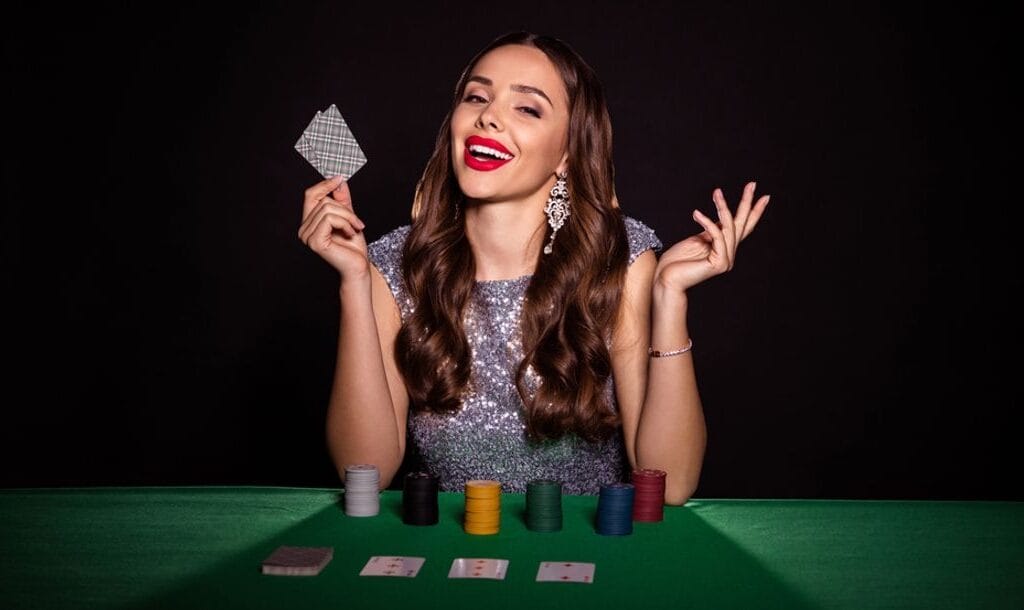 A women wearing a glittering gown at a poker table with stacks of chips.