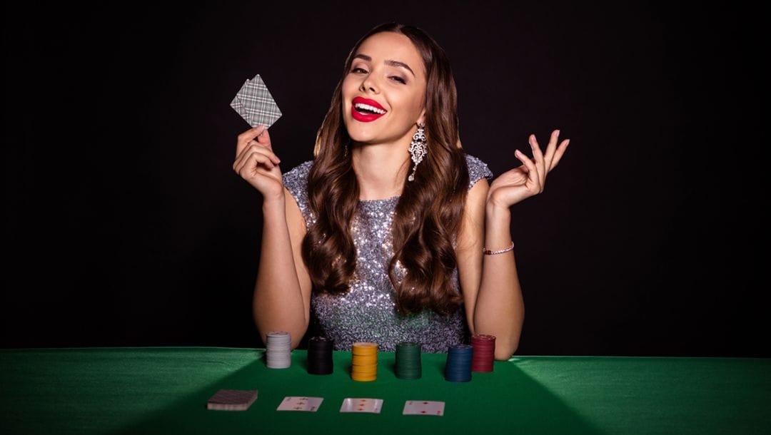 A women wearing a glittering gown at a poker table with stacks of chips.