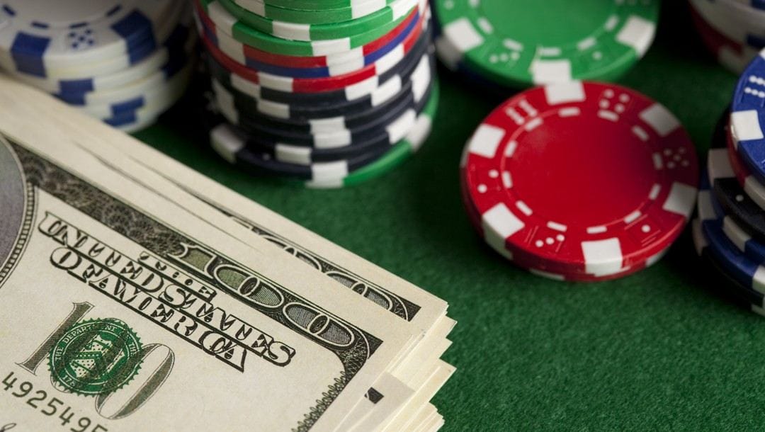 A stack of $100 bills next to stacks of poker chips.
