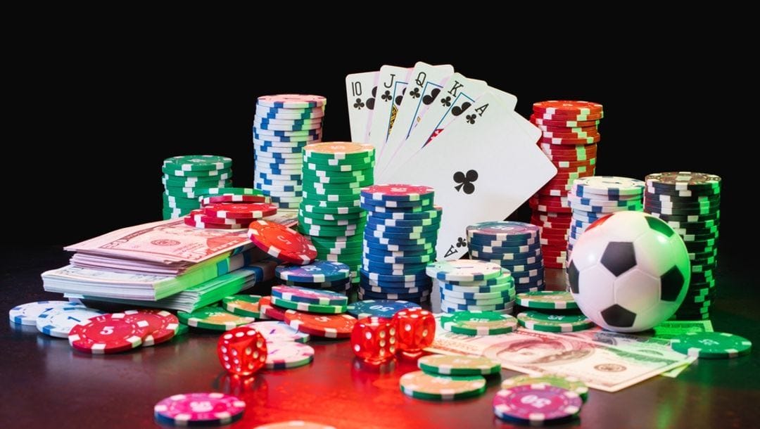 Stacks of casino chips, dollars, playing cards and dice.