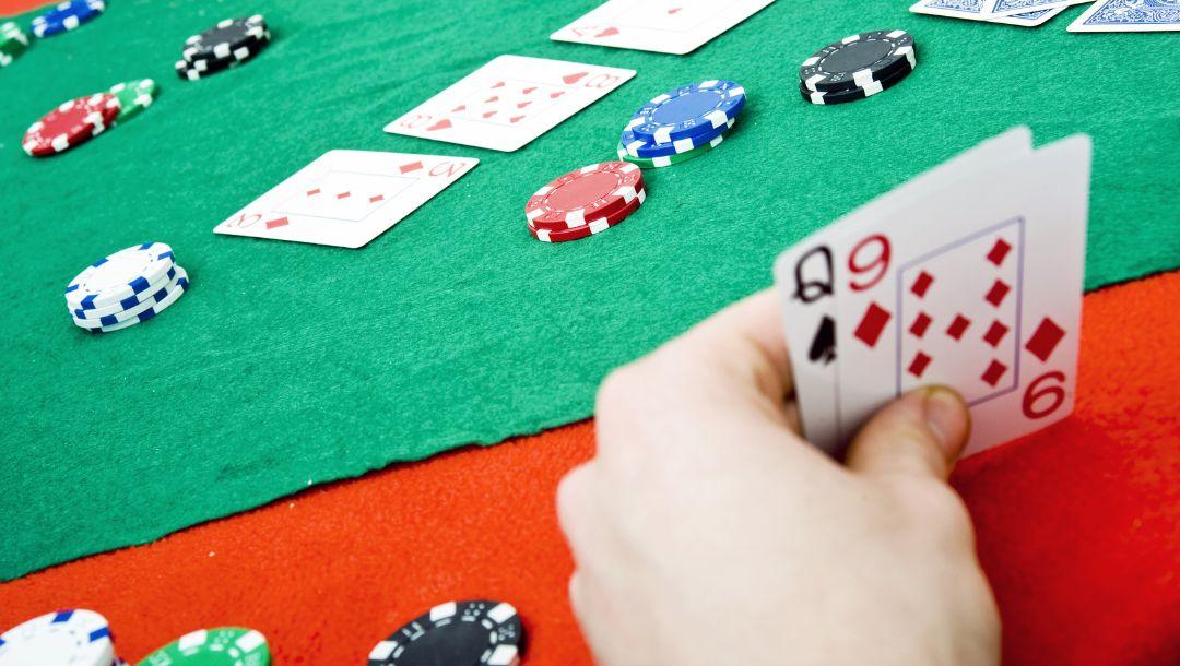 a person checks their hole cards, a queen of spades and a nine of diamonds, post flop during a game of poker