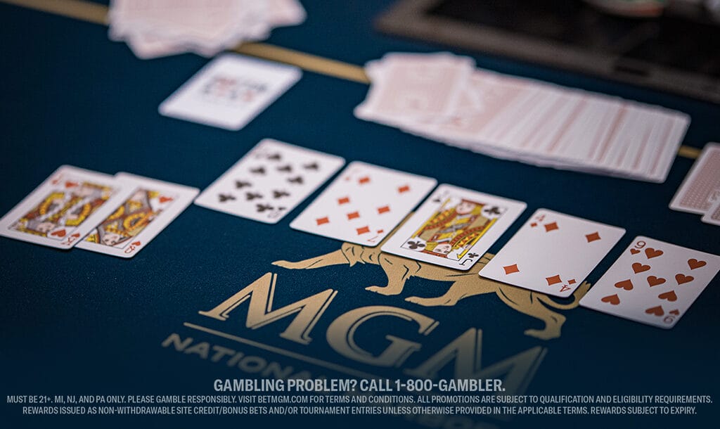 A poker game on a blue table with "MGM" logo, showing a winning hand of spade and heart cards. A stack of cards is fanned out in the background.