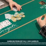 Poker game in progress at a Borgata Hotel Casino & Spa table, branded with BetMGM Poker. Two players are visible with large stacks of chips, and community cards are dealt on the table. One player has gone "All In" as indicated by a red chip.