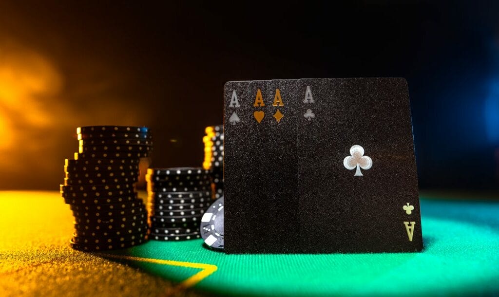 Black ace cards and black poker chips on a green felt table.