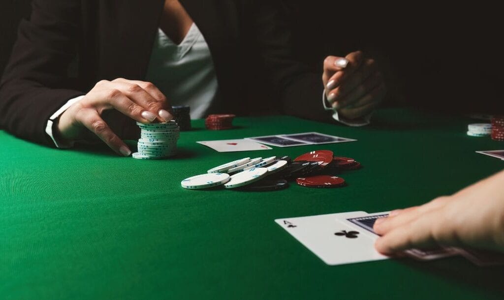 Two men engaged in a poker game at a table, surrounded by cards and poker chips.