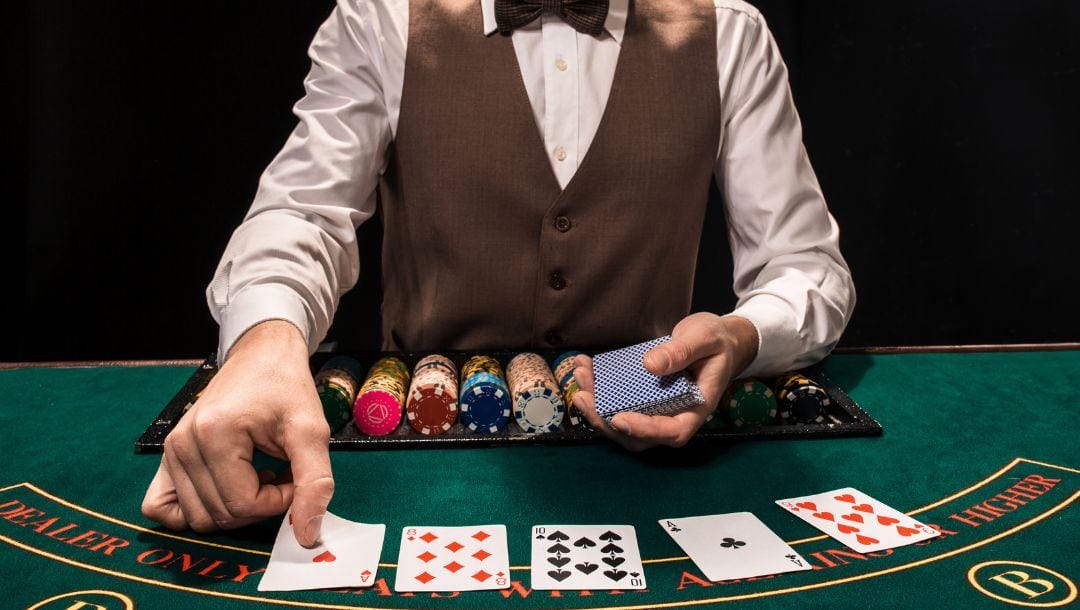 A dealer at a casino places the last community card on a green felt poker table.