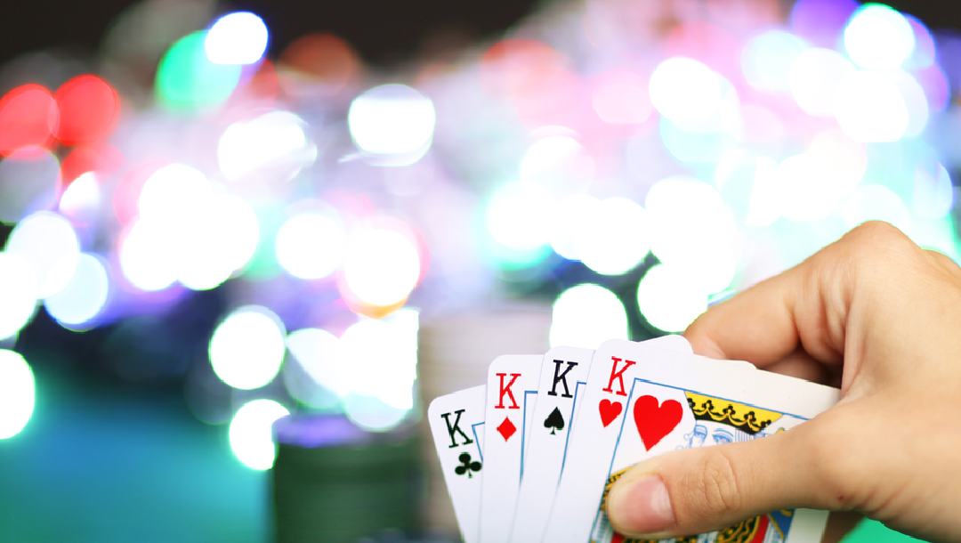 A person holding four kings in their hand