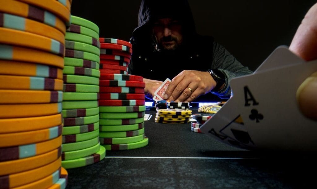 A game of high-stakes Texas Hold’em poker with two players sitting across from each other both lookin at their cards.