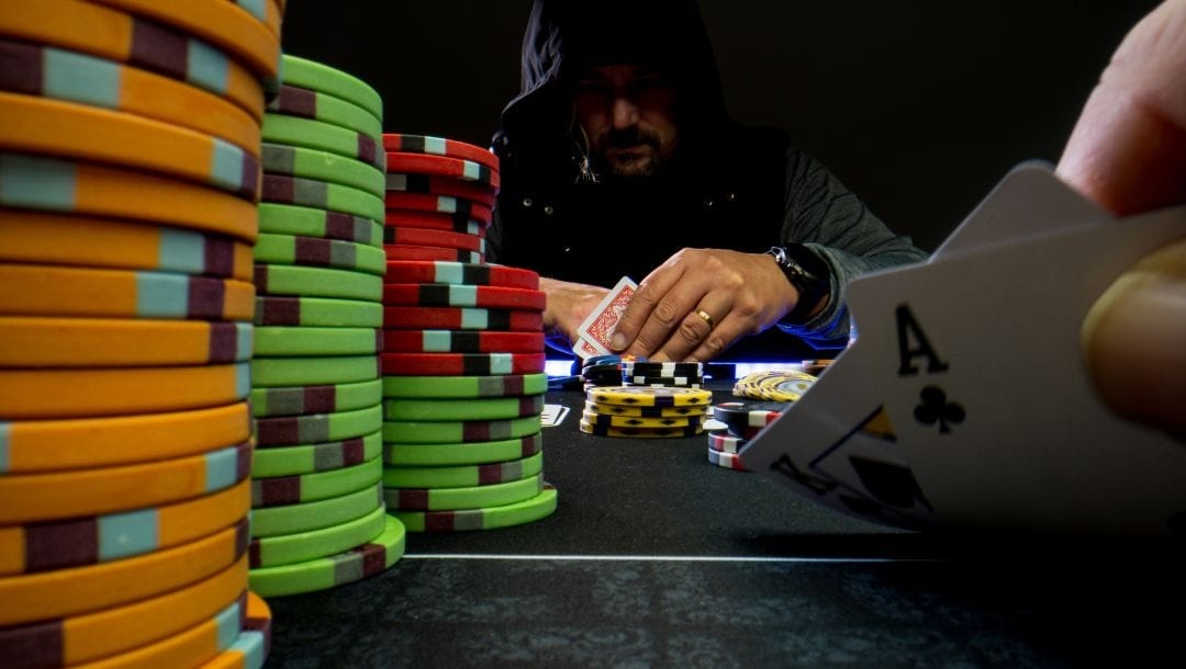 A game of high-stakes Texas Hold’em poker with two players sitting across from each other both lookin at their cards.