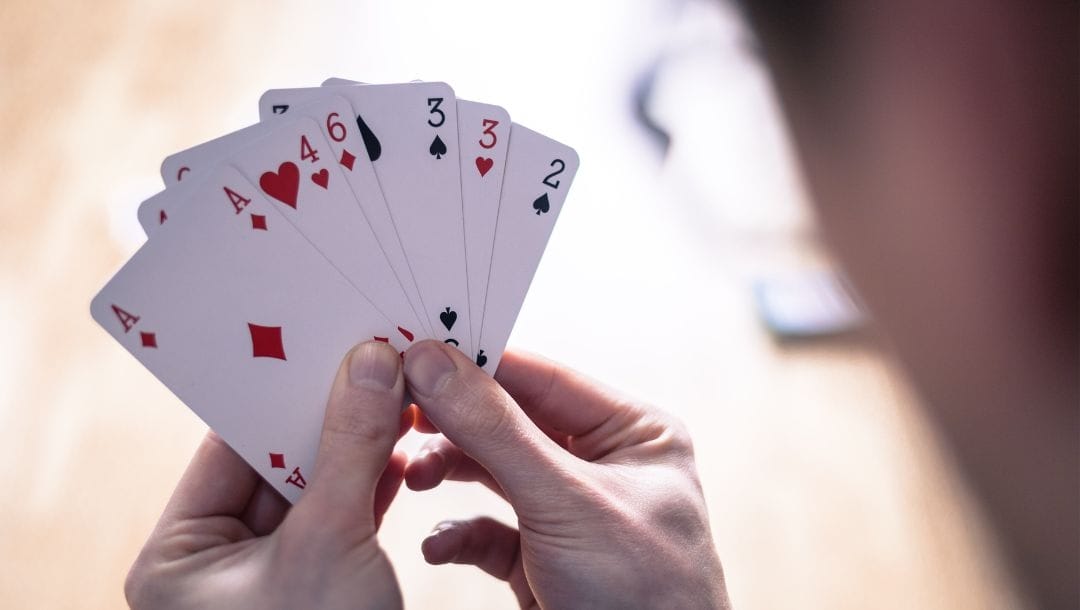 an over-the-shoulder view of a person looking at their poker hand of playing cards