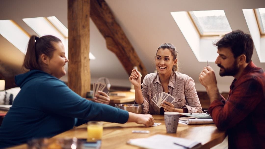 three friends playing poker at a table at home