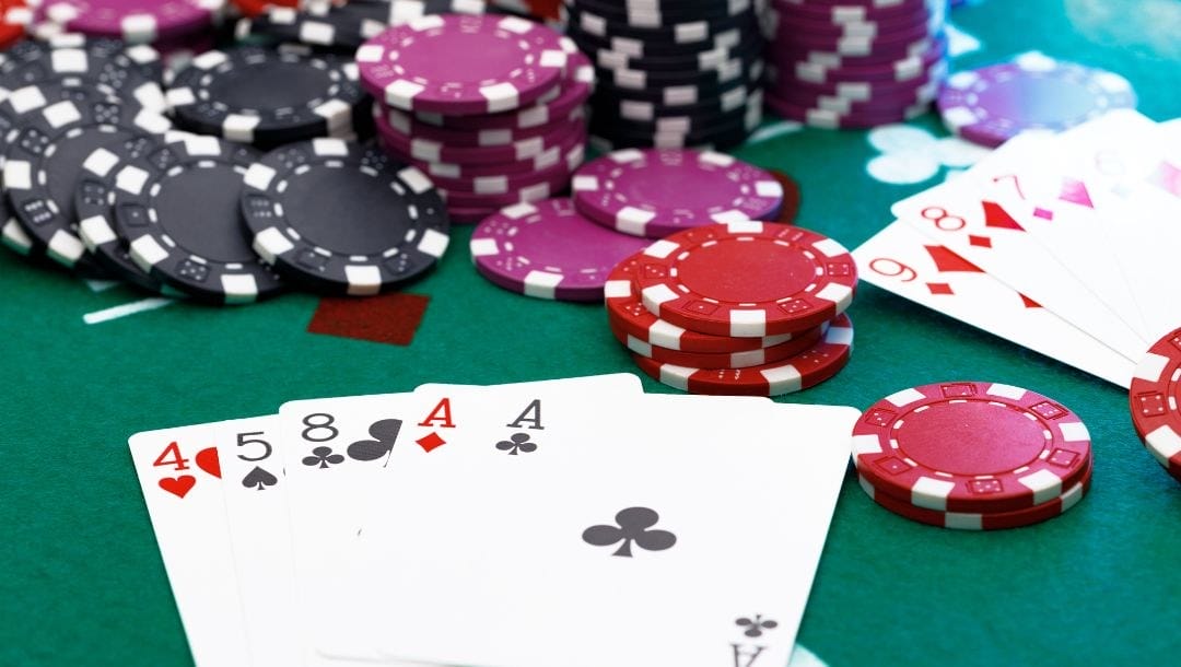 poker hands of playing cards and poker chips on a green felt poker table