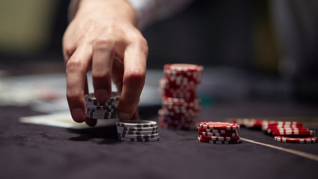 a man picking up from stacks of poker chips from a poker table