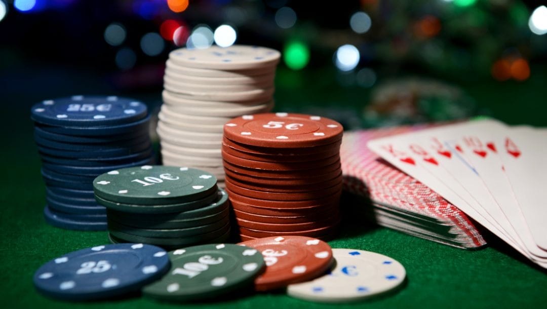 poker chips on a green felt poker chips with a deck of cards in the blurred background